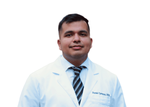 Studio headshot of Dr. Daniel Campos smiling in a white lab coat and dark patterned tie against a white background